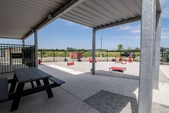 A picnic area with a black table and picnic benches under a metal roof.at Linc, Des Moines, 50309  